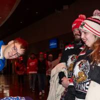 Hunter Rich helping two alum at table spin the prize wheel